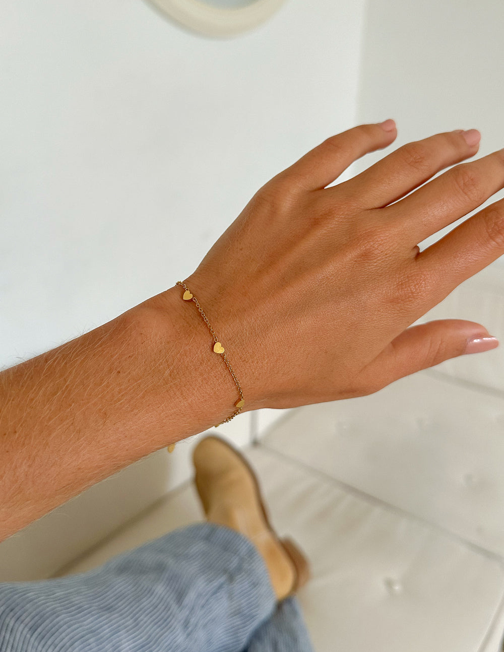 Gold heart charm bracelet on wrist, small round bead links and heart accents