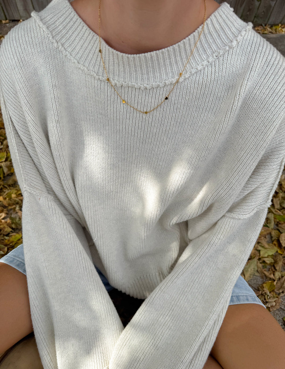 Gold tone layered heart link necklace resting on knit sweater neckline