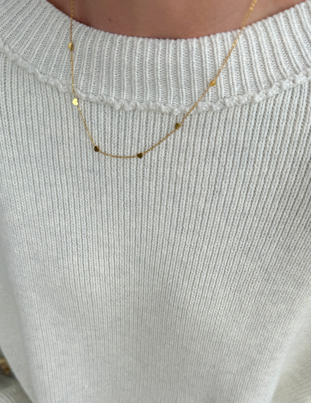 Close-up gold heart link necklace with small linked charms and fine chain