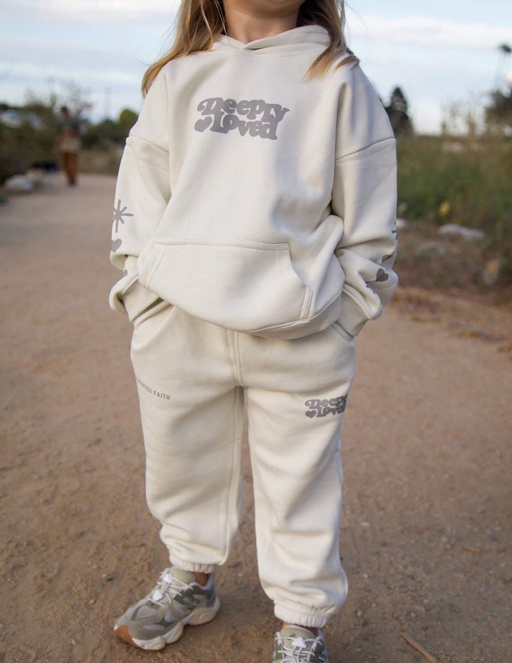 Kids hoodie in off-white with front “Sleepy Loved” text graphic and pullover hood