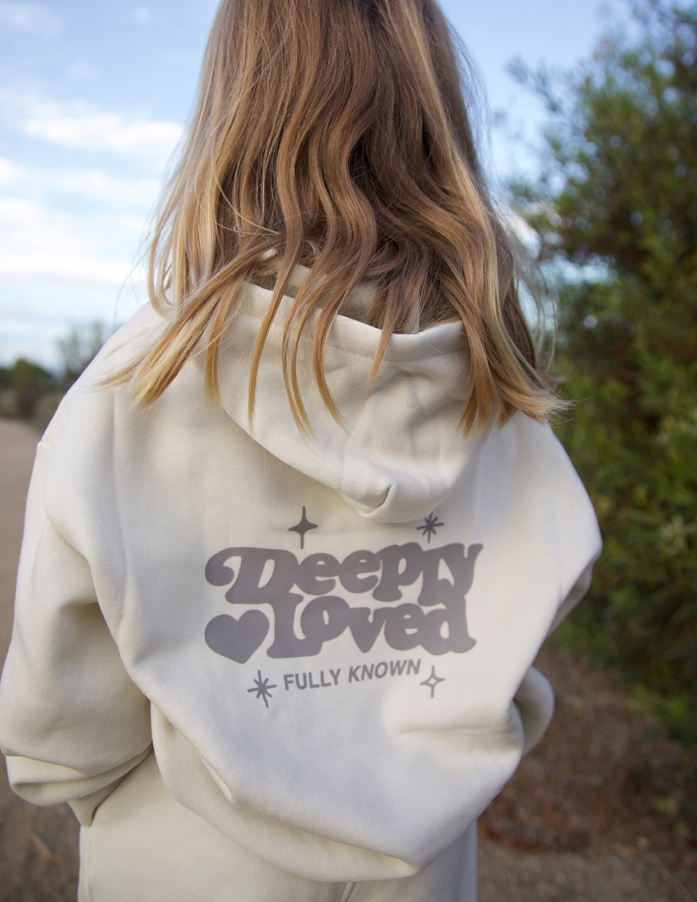 Kids hoodie back view in off-white with large “Sleepy Loved” heart and star print