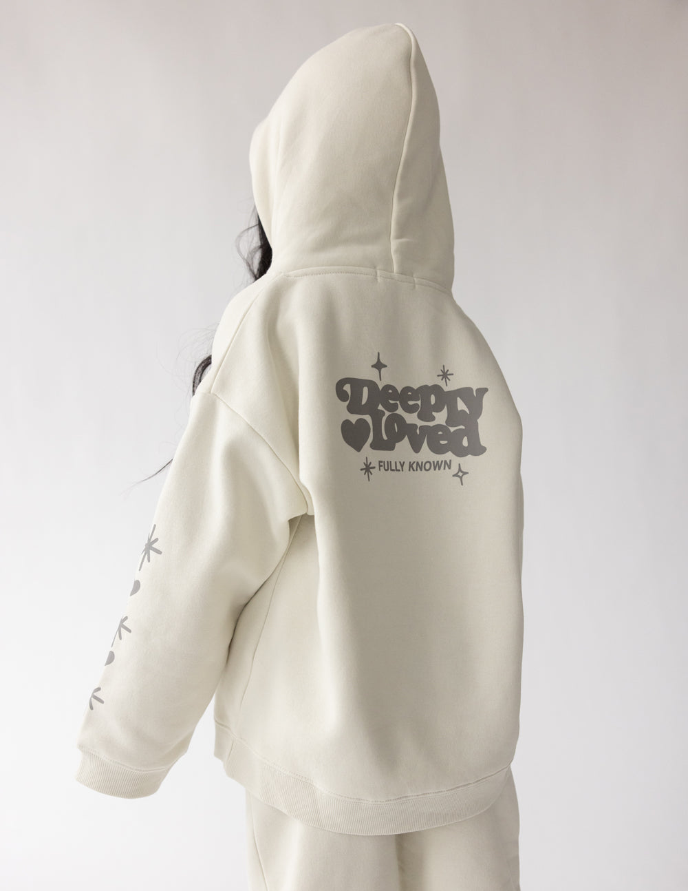 Kids hoodie back view in off-white with centered “Sleepy Loved” graphic
