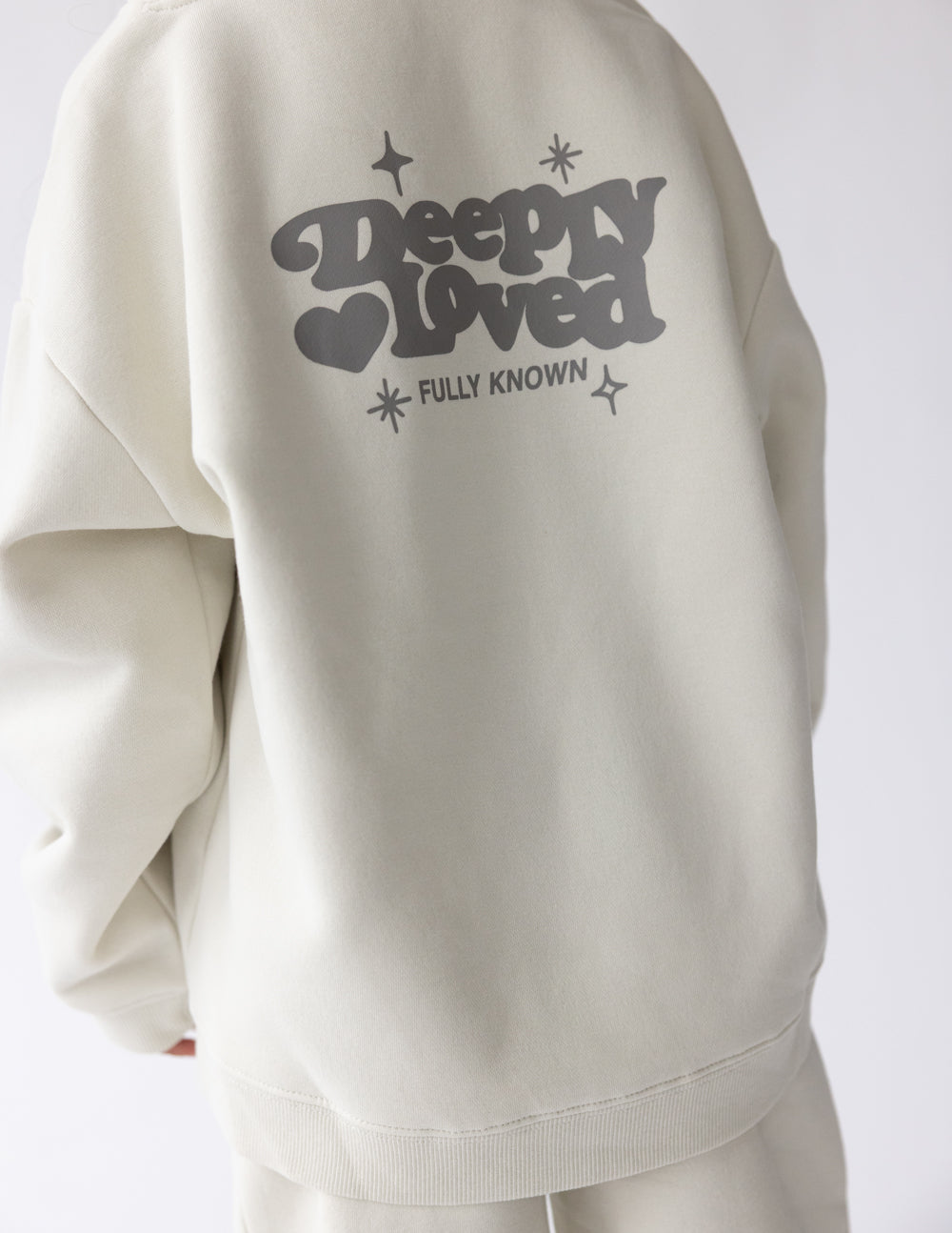 Kids hoodie back view off-white with “Sleepy Loved” text, hearts, and sparkles