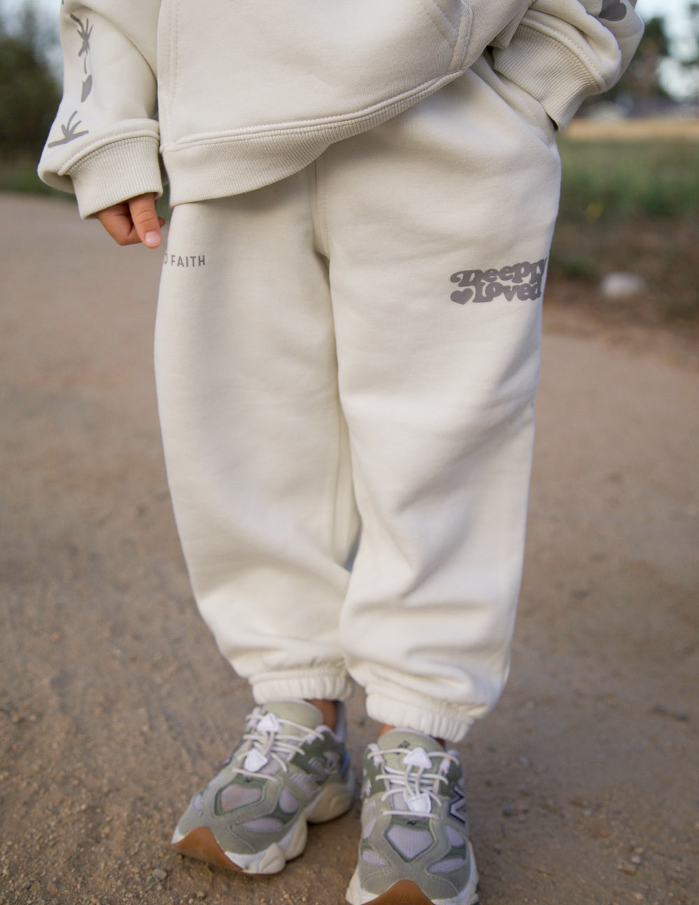Kids cream sweatpants with printed logo on left thigh, cuffed ankle hems