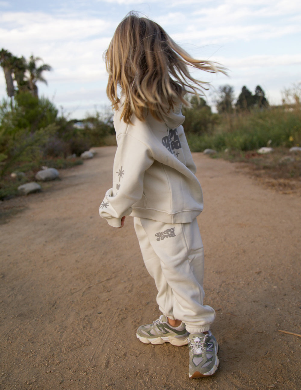 Kids cream sweatpants with printed logo on leg, elastic cuffs and relaxed fit