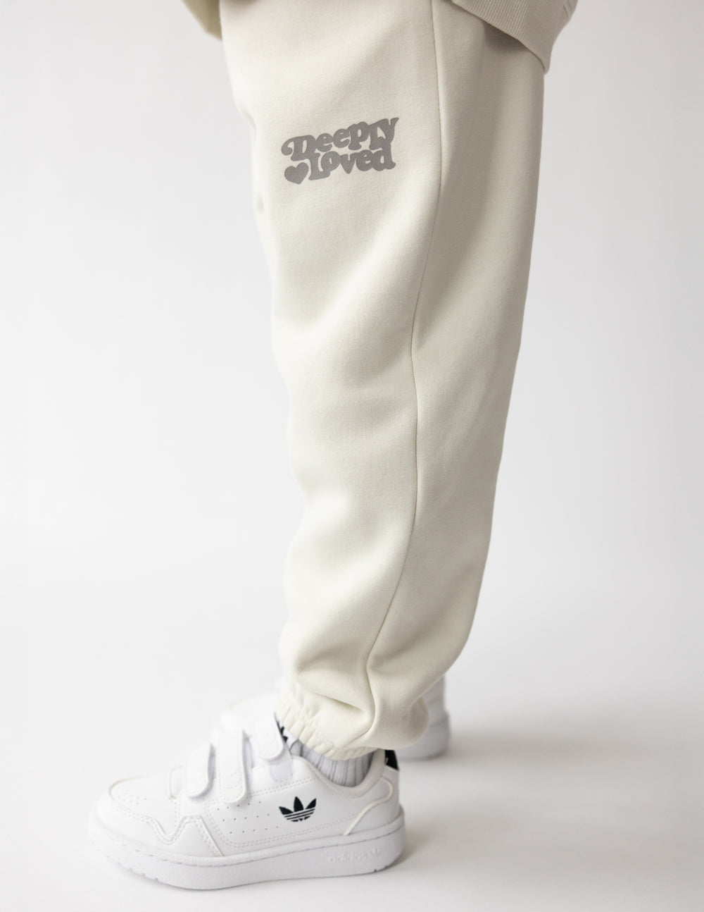 Kids cream sweatpants with printed logo on thigh and elastic ankle cuffs