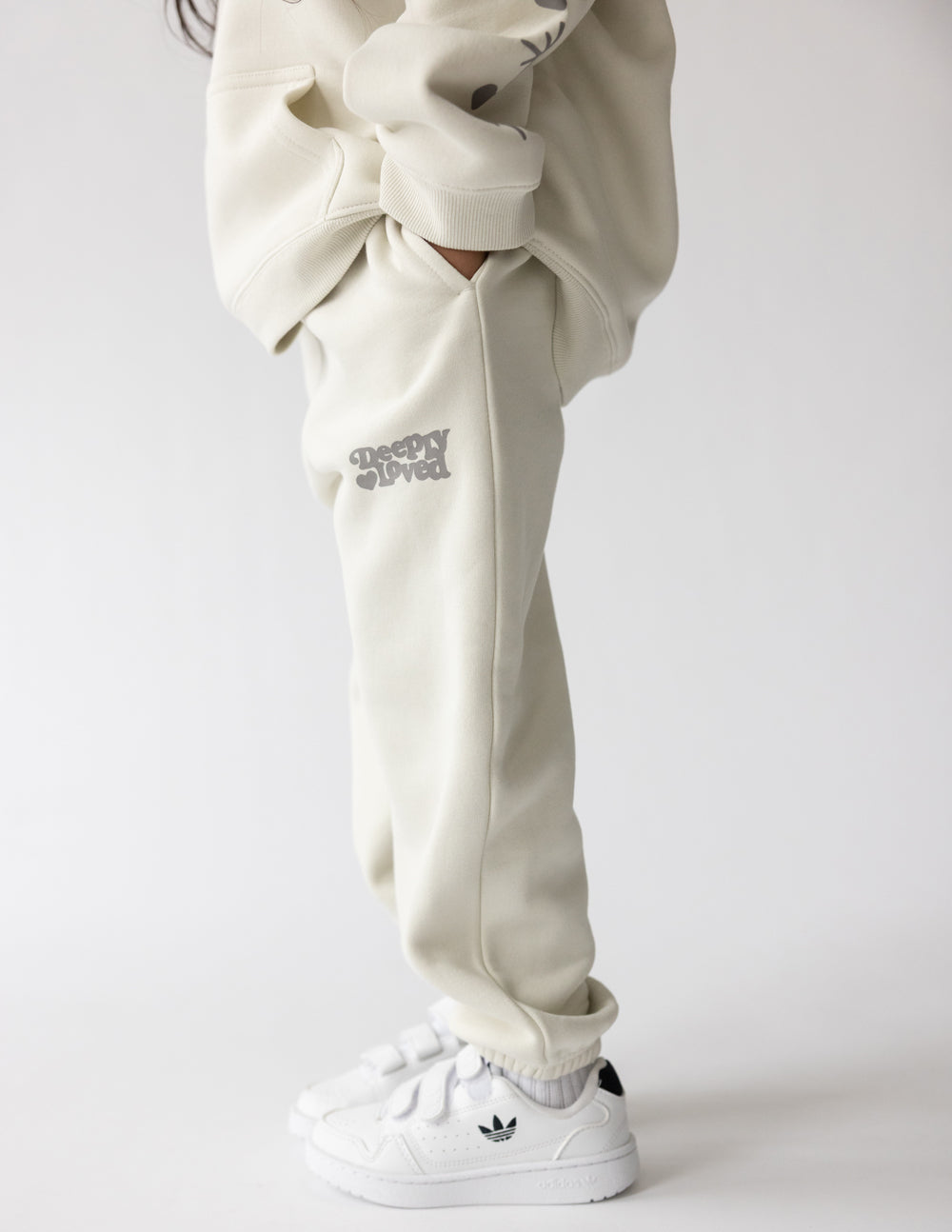 Kids cream sweatpants with printed logo on thigh, elastic waistband and cuffed hem