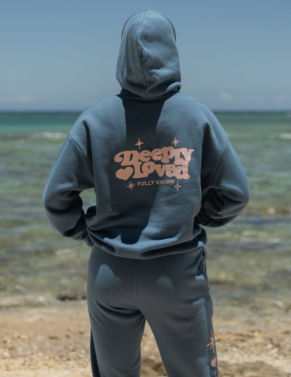 Blue unisex hoodie with hood, kangaroo pocket, and centered back logo graphic
