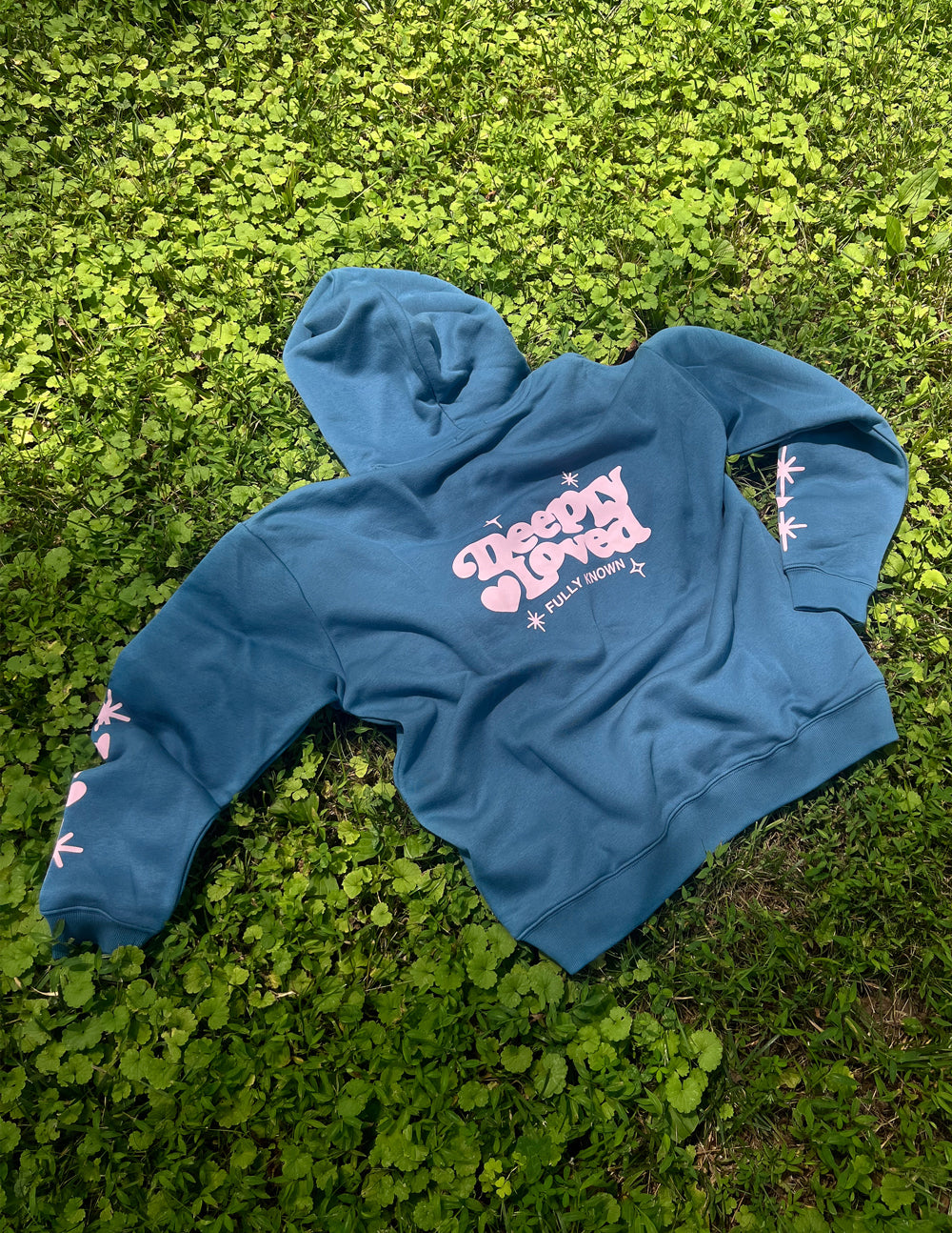 Blue unisex hoodie laid out with hood, chest graphic, and starburst sleeve prints
