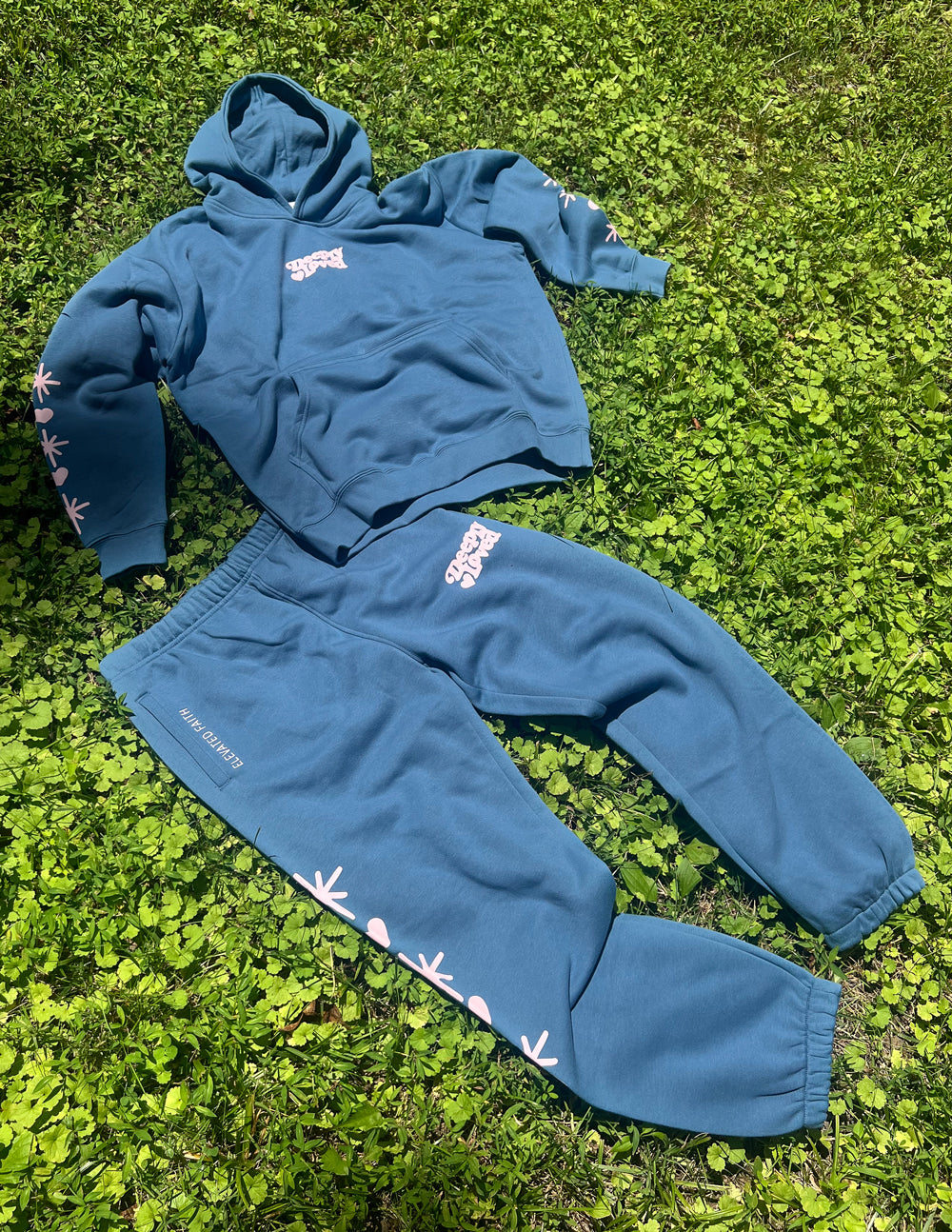 Unisex blue sweatpants with star and flower prints, elastic cuffs, on grass