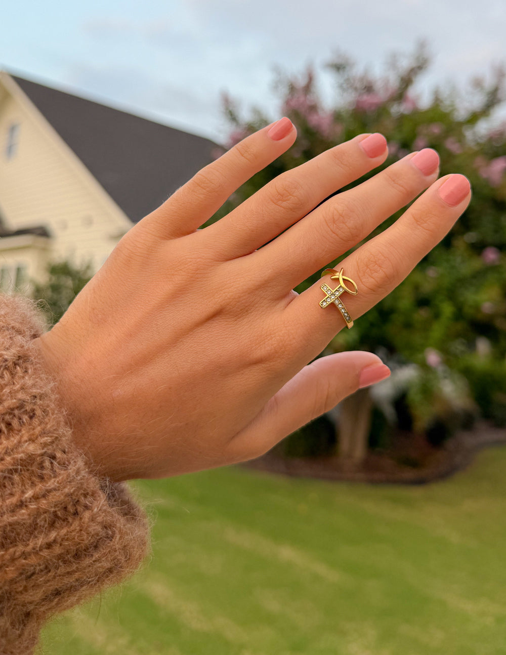 Gold-tone ring with cross charm and clear stones on slim band