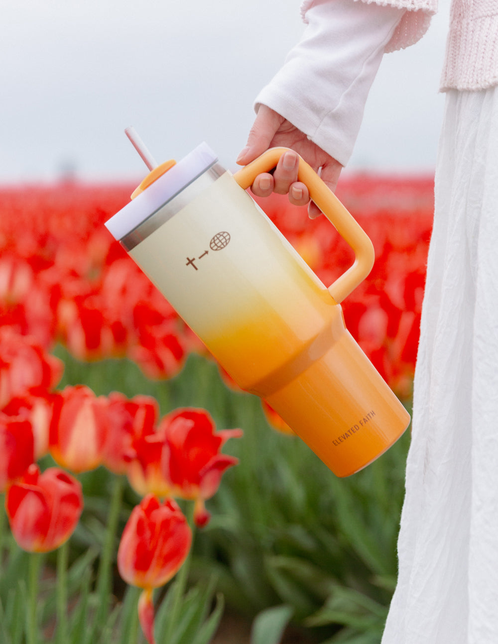 40 oz faith tumbler with orange straw and cream-to-orange gradient, held in hand