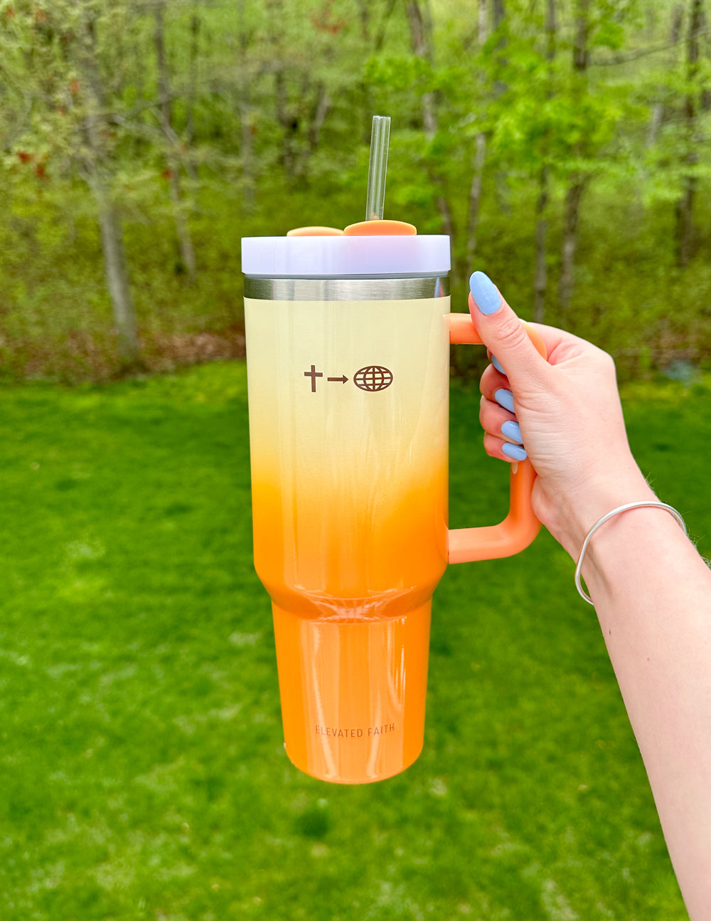 40 oz faith tumbler with straw, silver lid, and cream-to-orange gradient held by handle