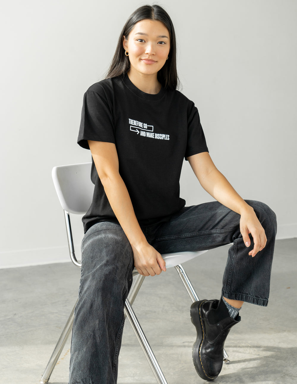 Unisex T-shirt, black, with small white arrow-and-text graphic at the chest