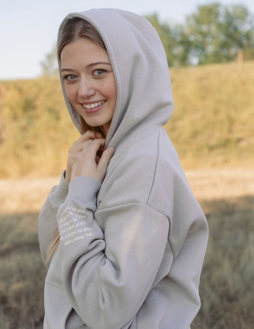 Grey unisex hoodie with hood up and “do not fear.” chest print.