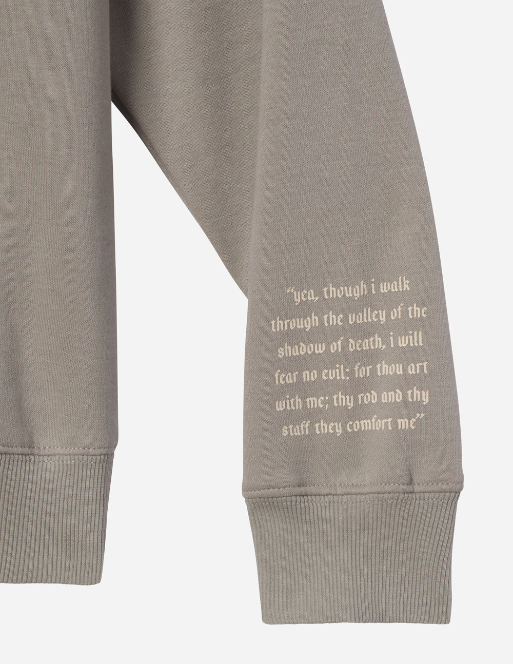 Grey hoodie sleeve with quote print and ribbed cuff; hoodie's side seam visible.
