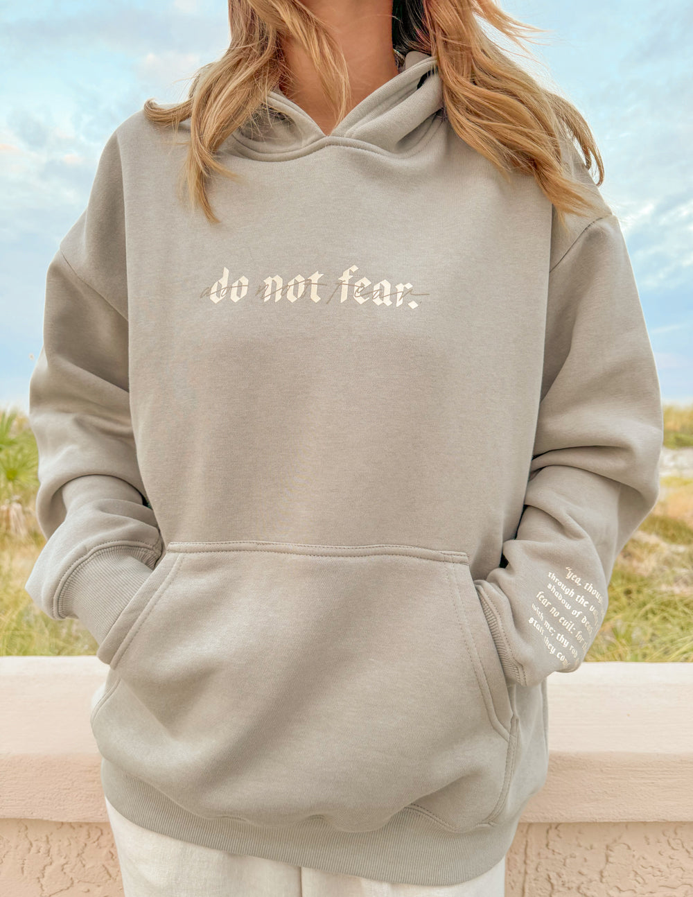 Grey unisex hoodie with hood and “do not fear.” chest print, front pocket shown.