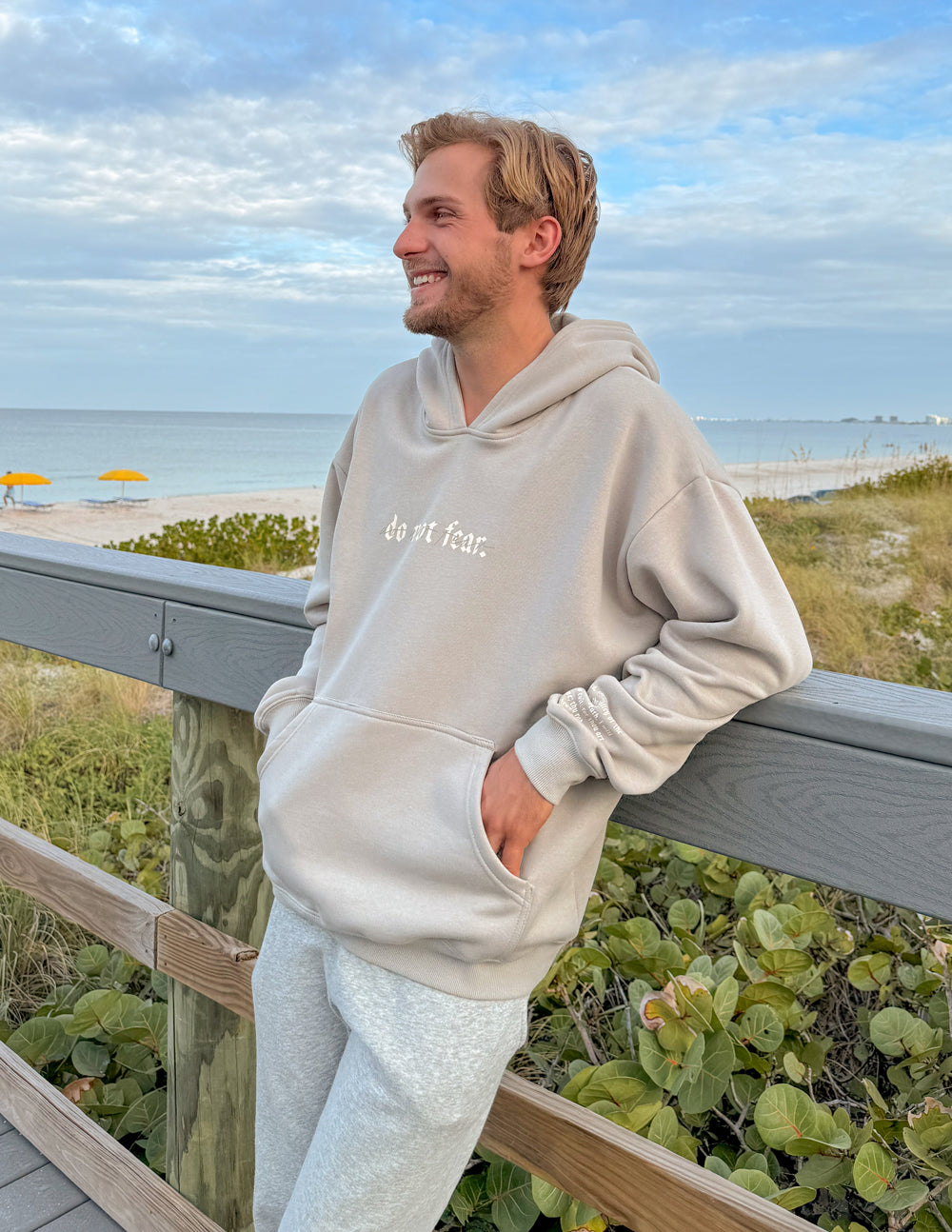 Grey unisex hoodie worn sideways; “do not fear.” chest print and front pocket visible.
