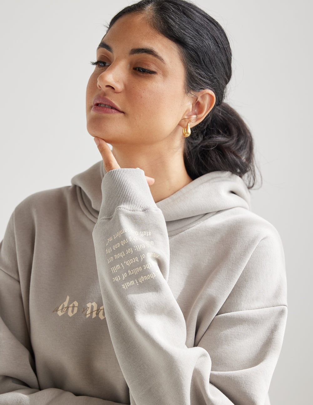 Grey unisex hoodie close-up with hood and sleeve graphic text