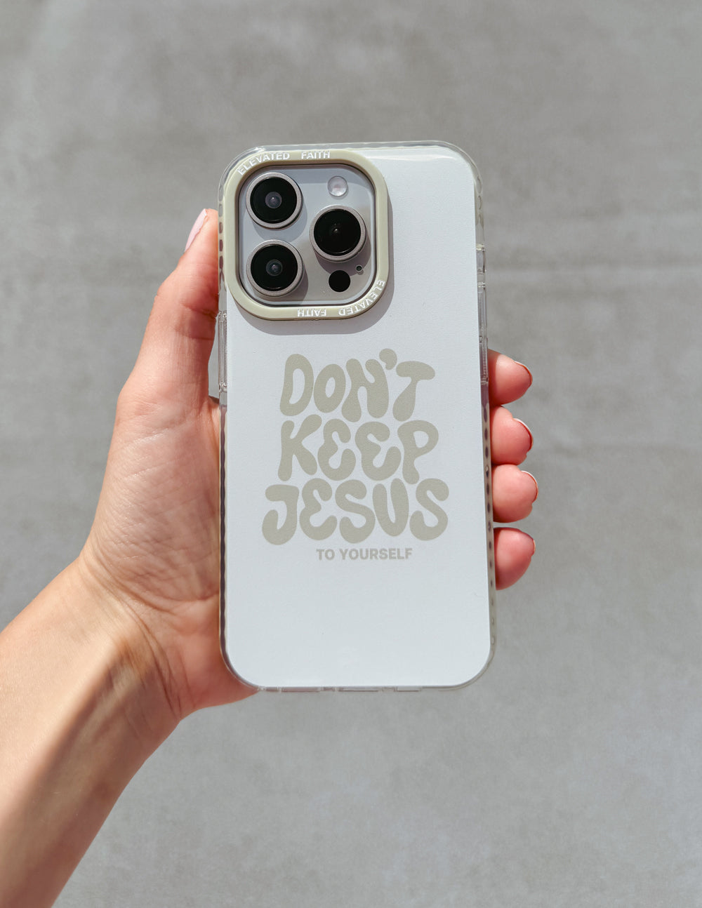 White phone case held in hand with "Don't Keep Jesus to Yourself" text and camera cutouts