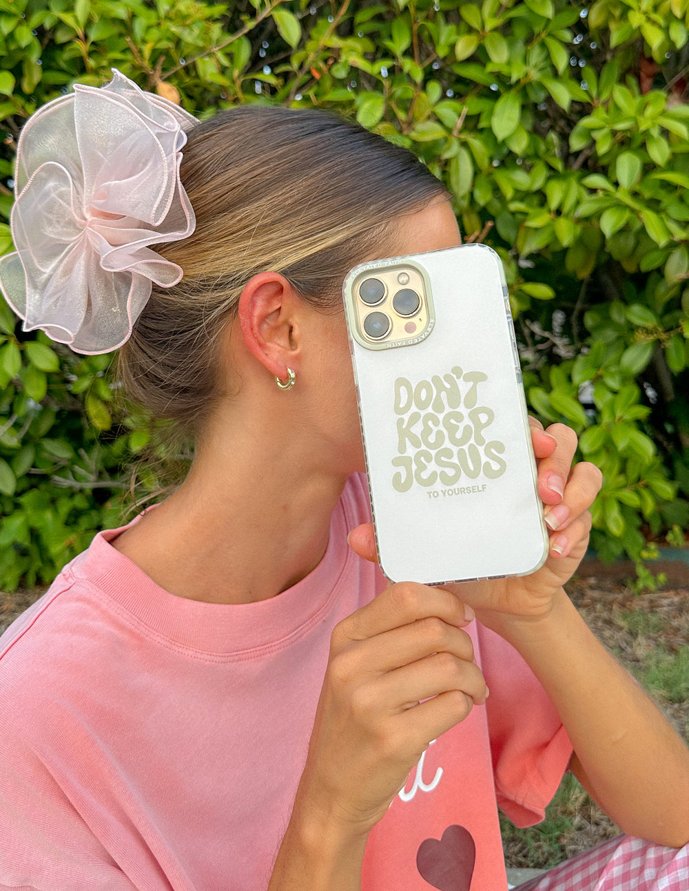 White phone case with "Don't Keep Jesus to Yourself" text, held near face and camera cutout