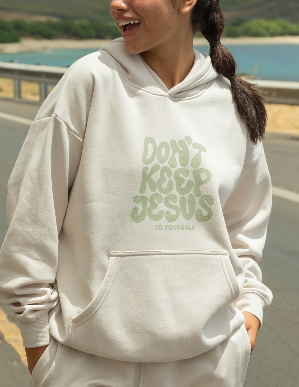 Cream unisex hoodie with green "DON'T KEEP JESUS" graphic on chest, front kangaroo pocket