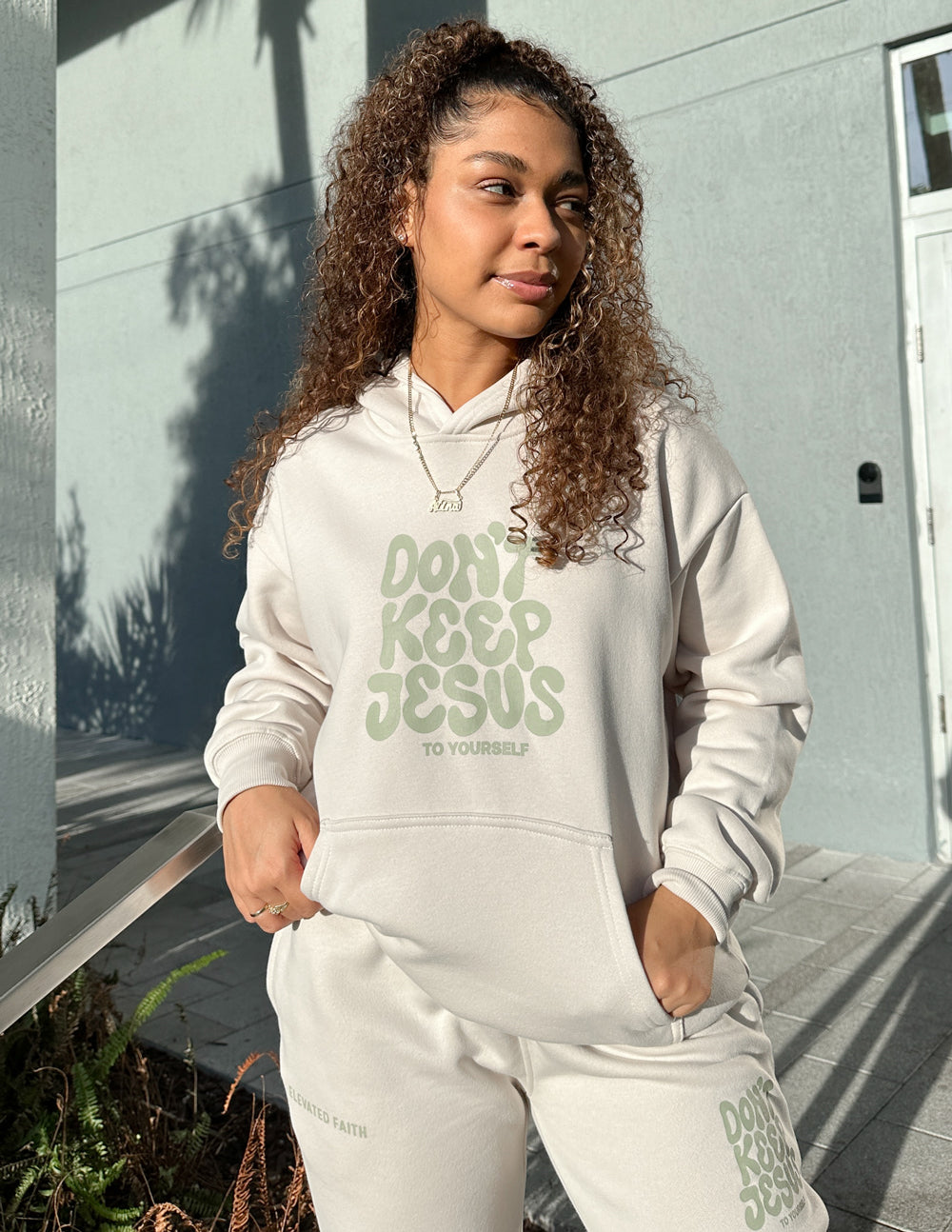Cream unisex hoodie and jogger set with green "DON'T KEEP JESUS" front graphic, hood