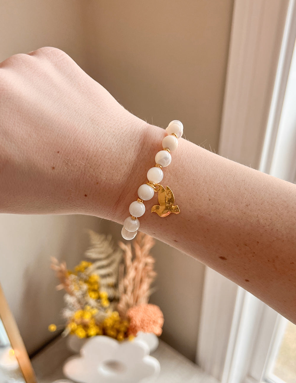 White pearl beaded bracelet with a gold dove charm