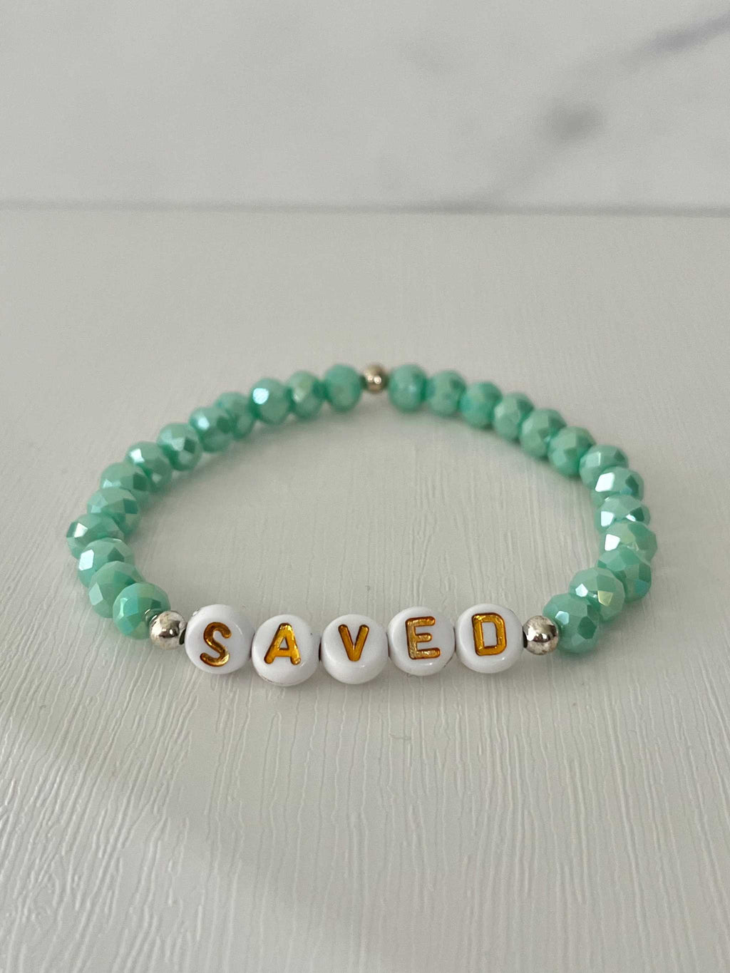 Mint green beaded bracelet with 'SAVED' letter beads and small gold spacers
