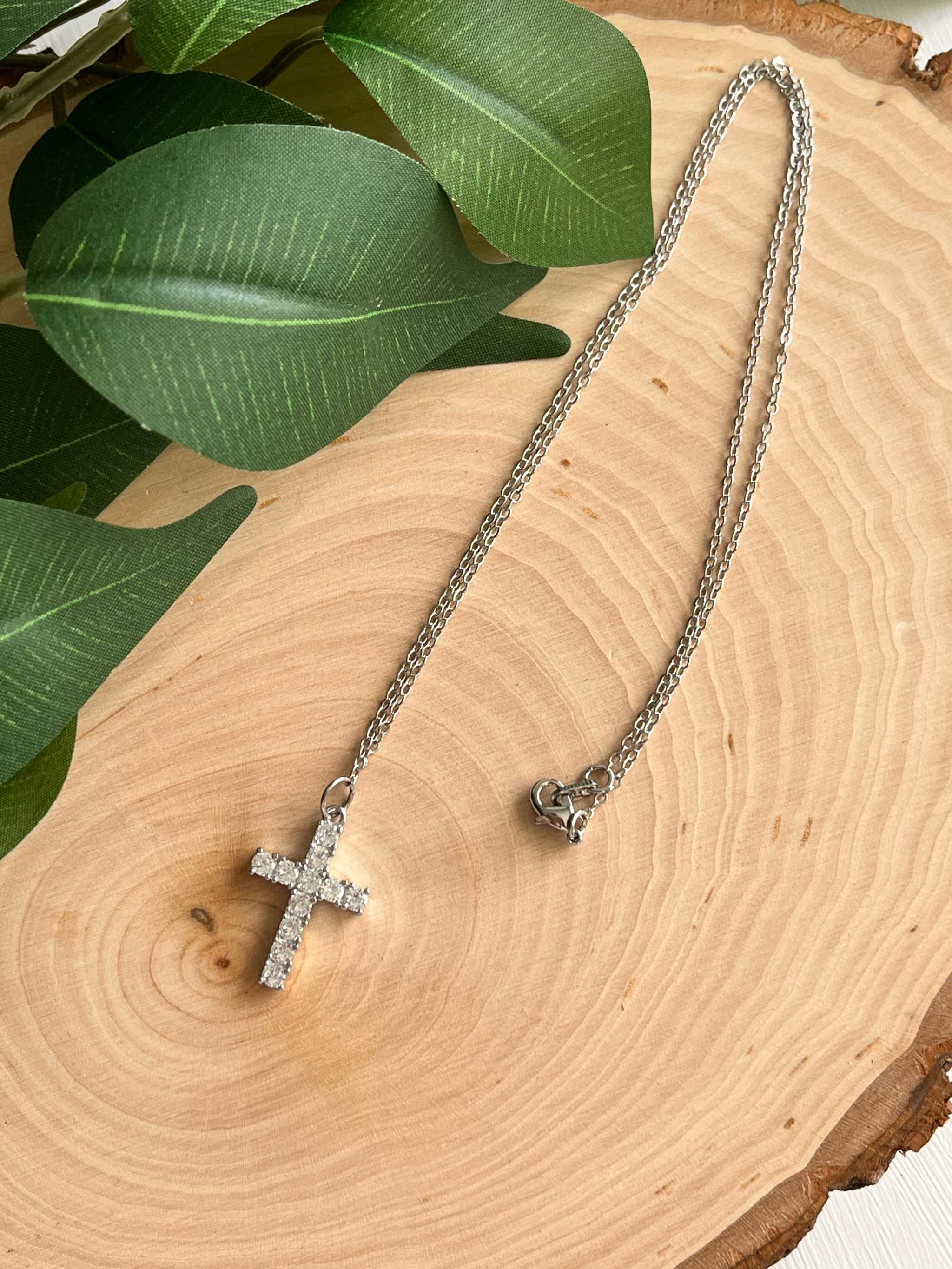Silver cross pendant necklace with rhinestone cross and chain ends visible