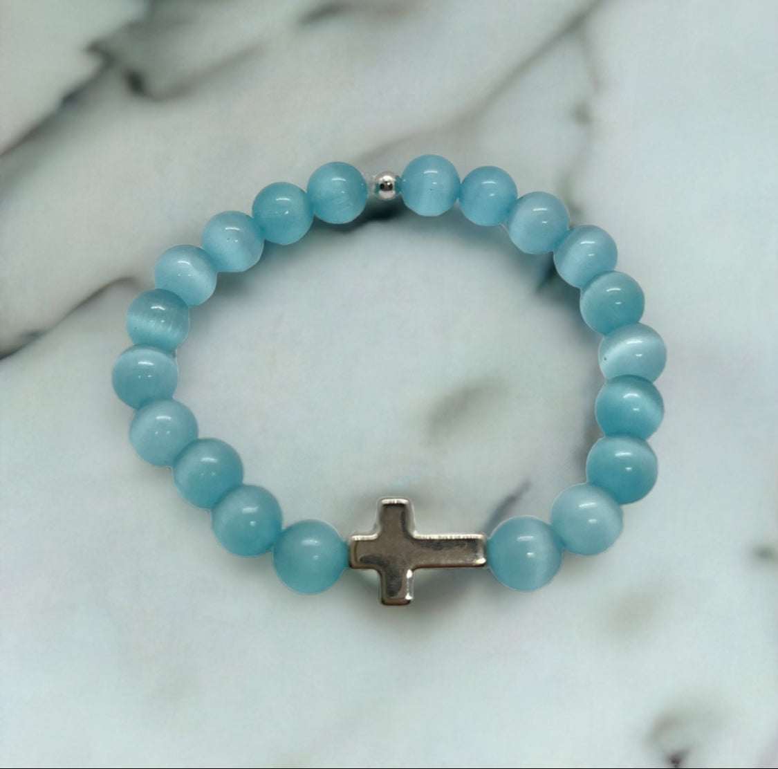 Light teal beaded cross bracelet featuring a silver cross center charm.