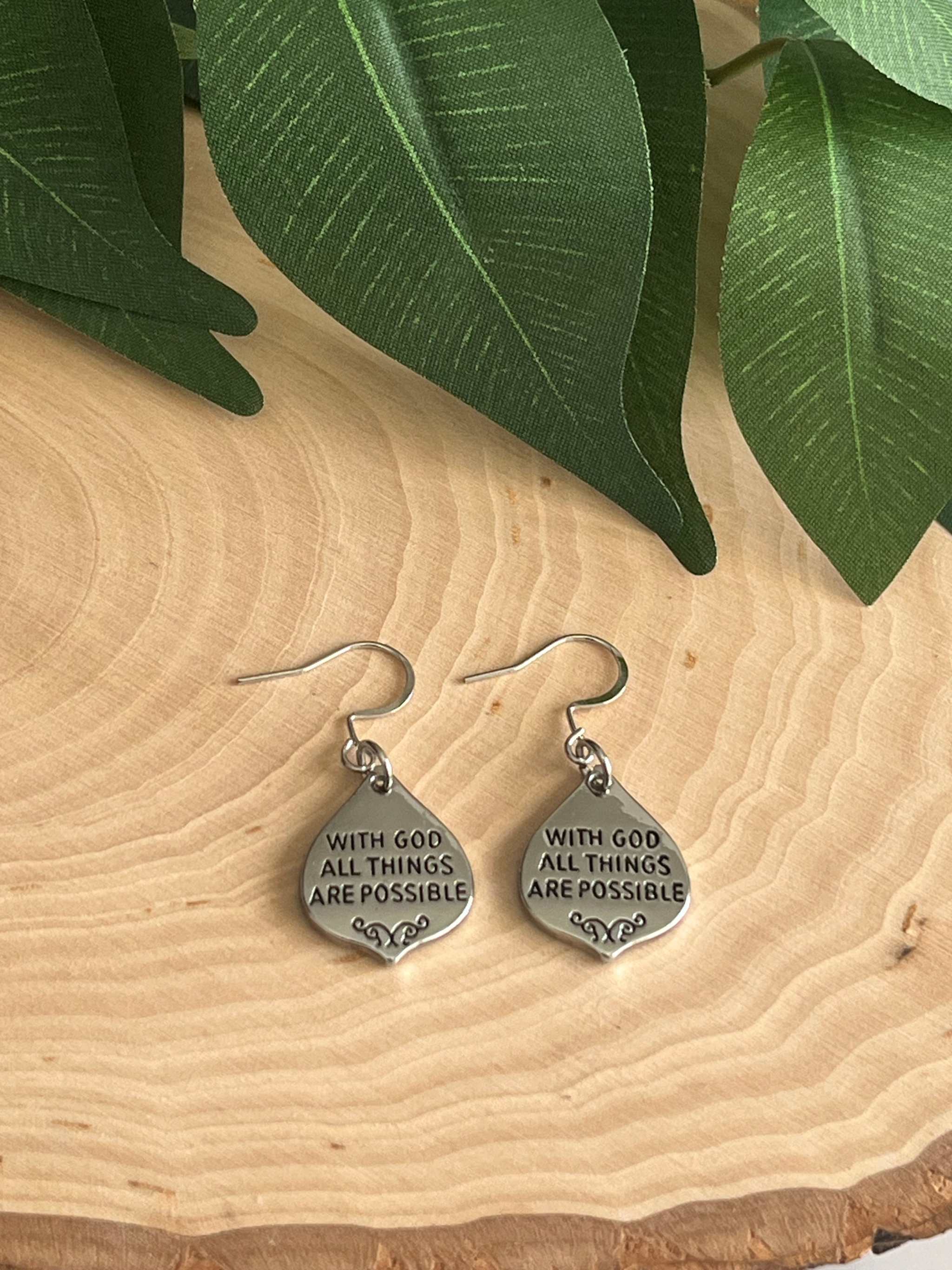 Silver dangle earrings with engraved “With God all things are possible” text.