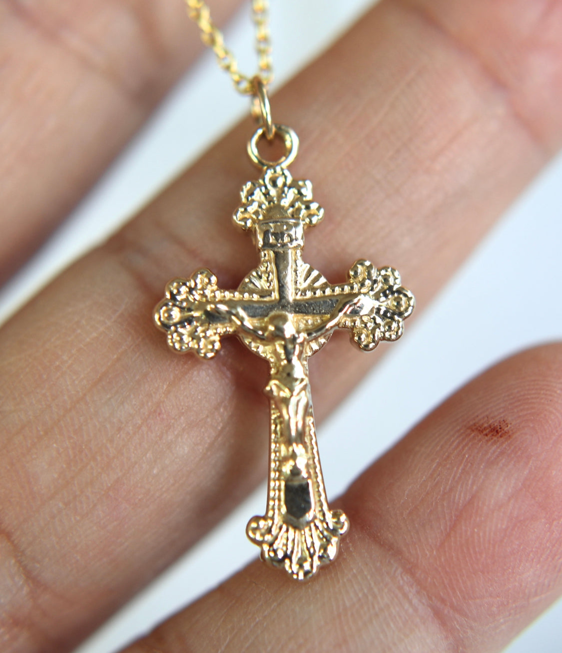 14k gold crucifix pendant on a chain, front view with ornate detailing.