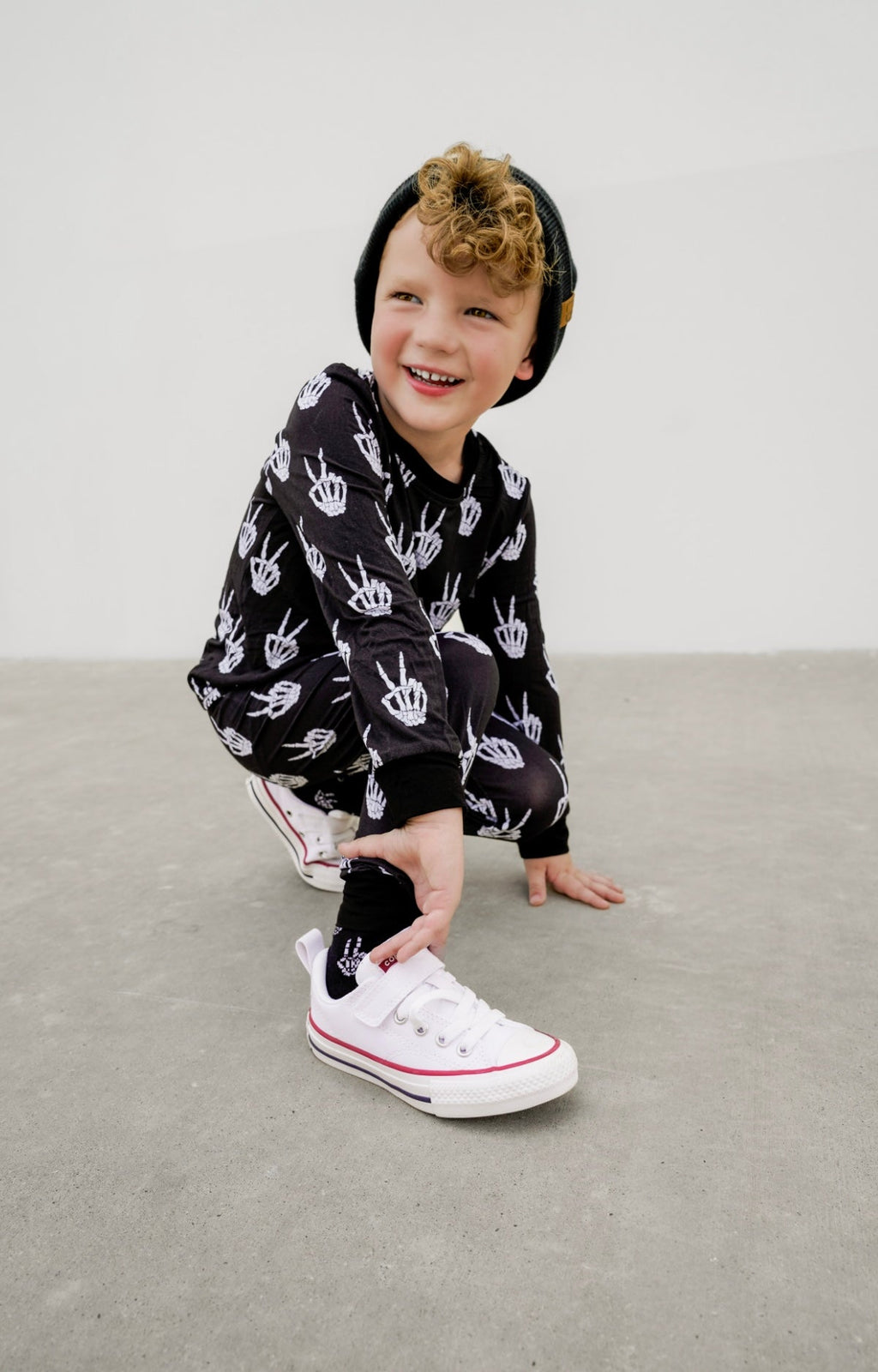 Kids black pajama set with white skeleton-hand print, long sleeves and cuffs.