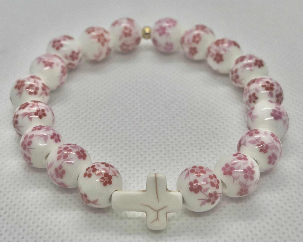 White-and-pink floral bead cross bracelet with a white cross charm.