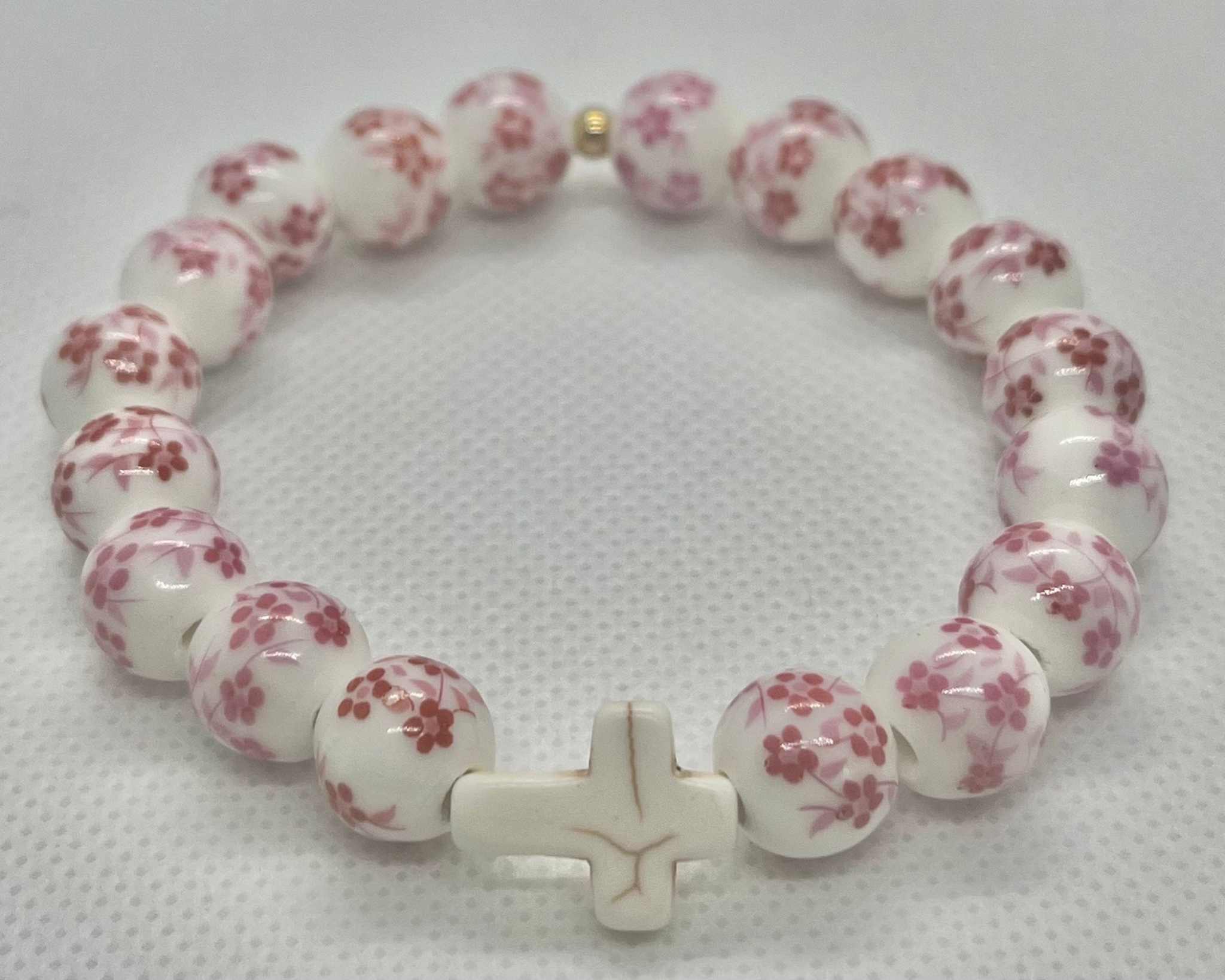 White-and-pink floral bead cross bracelet with a white cross charm.