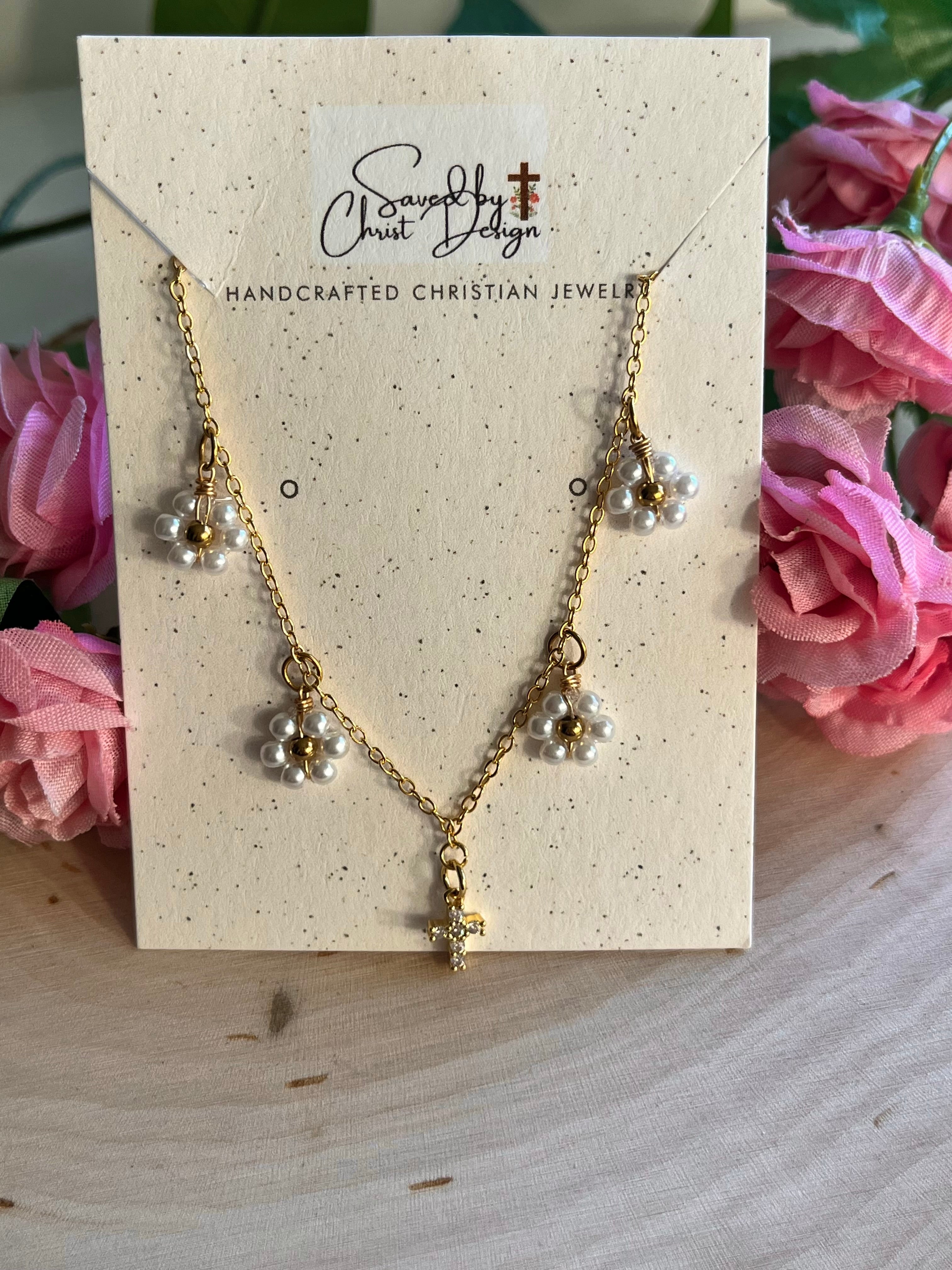 Gold cross pendant necklace set on a jewelry card with white daisy charms