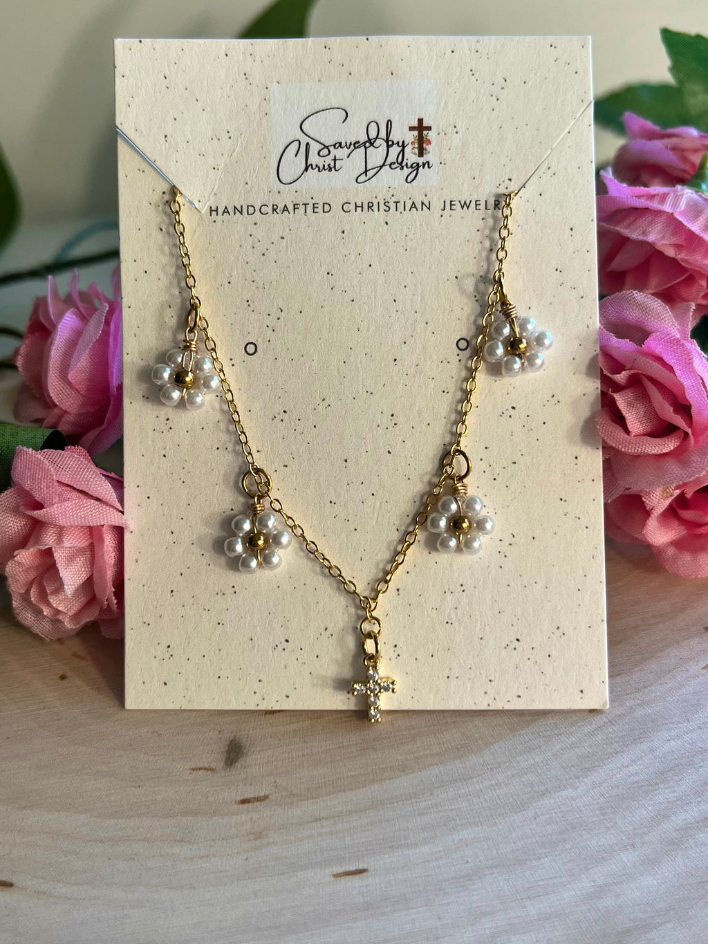 Gold cross pendant necklace on a jewelry card with white daisy charms