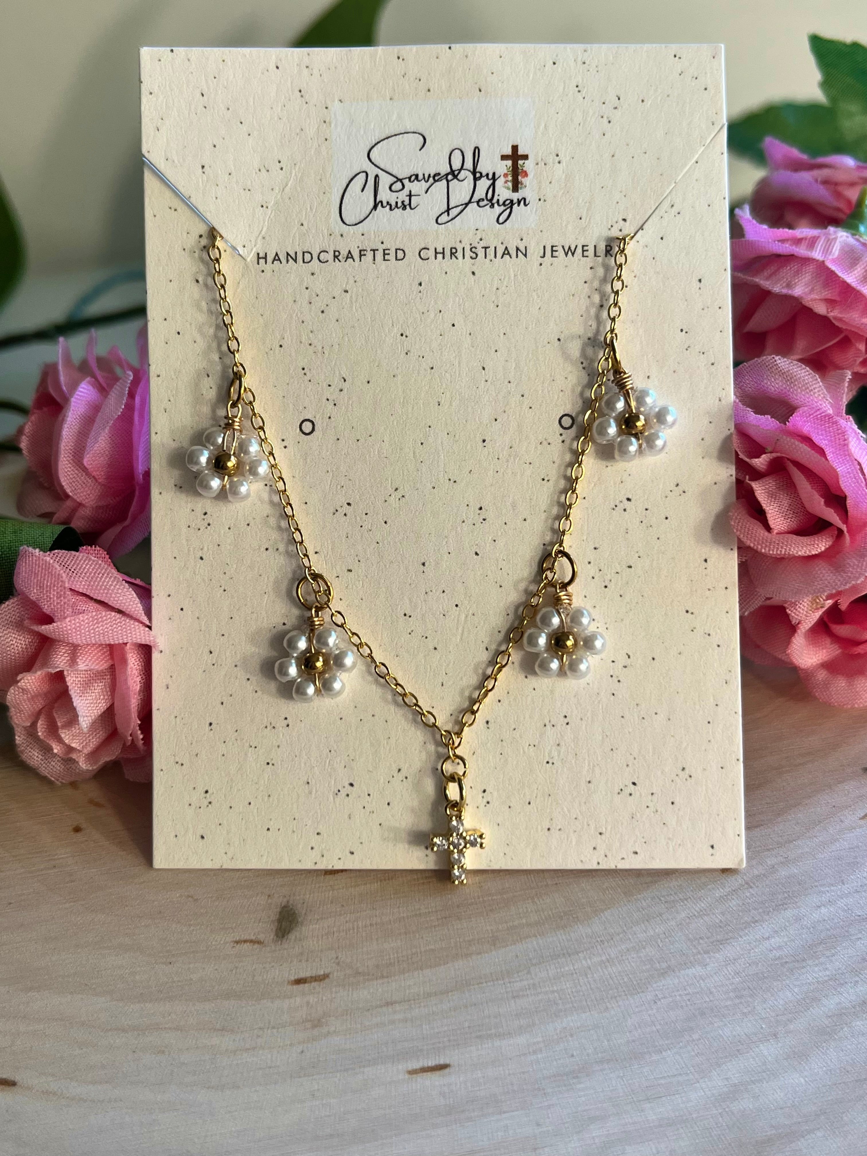 Gold cross pendant necklace on a jewelry card with white daisy charms