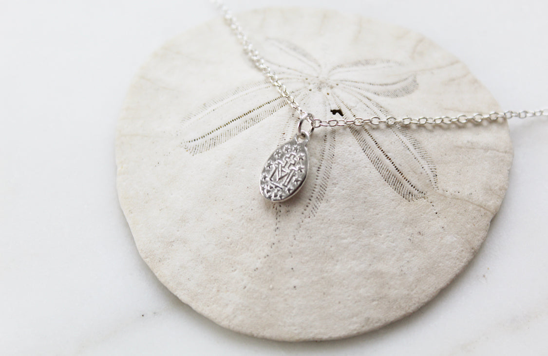 Oval sterling silver medal charm necklace on chain with bail, close-up