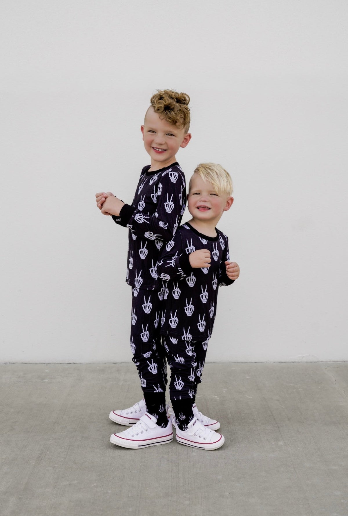 Kids black long-sleeve pajama set with white skeleton-hand pattern, matching bottoms.