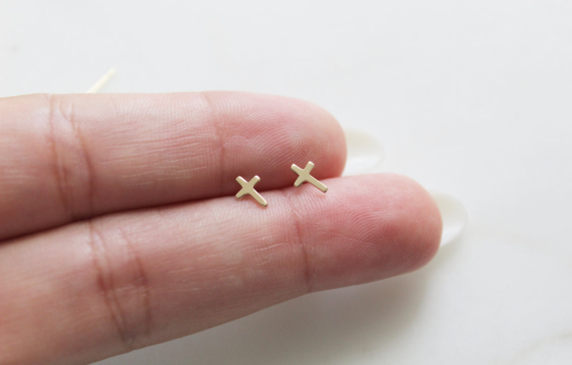 14k gold cross stud earrings close-up on open hand, cross tops visible