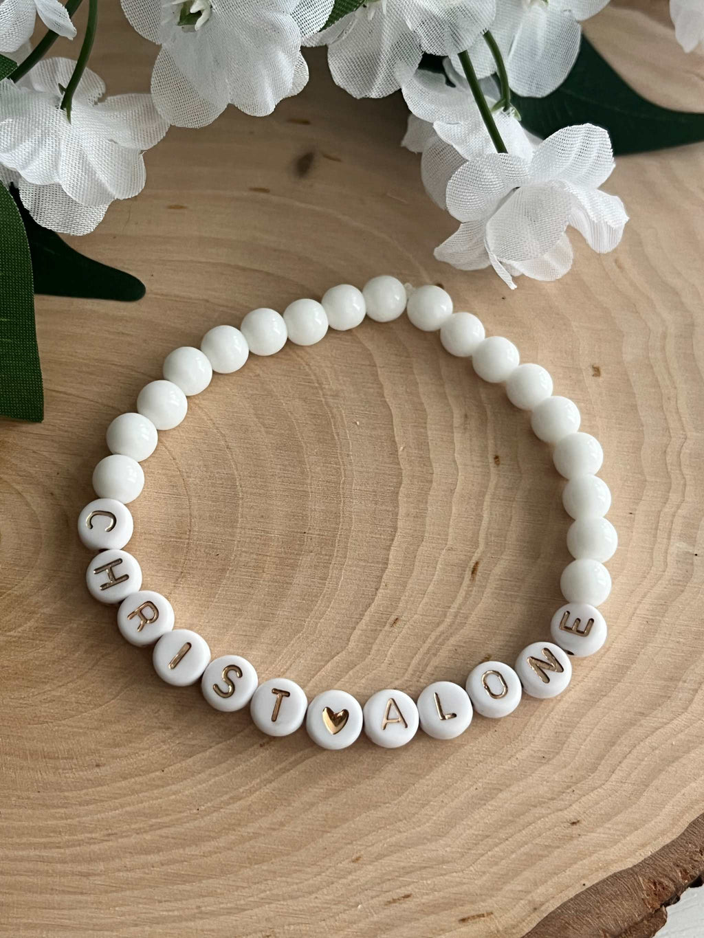 White bead bracelet with round letter beads spelling "CHRIST ALONE"