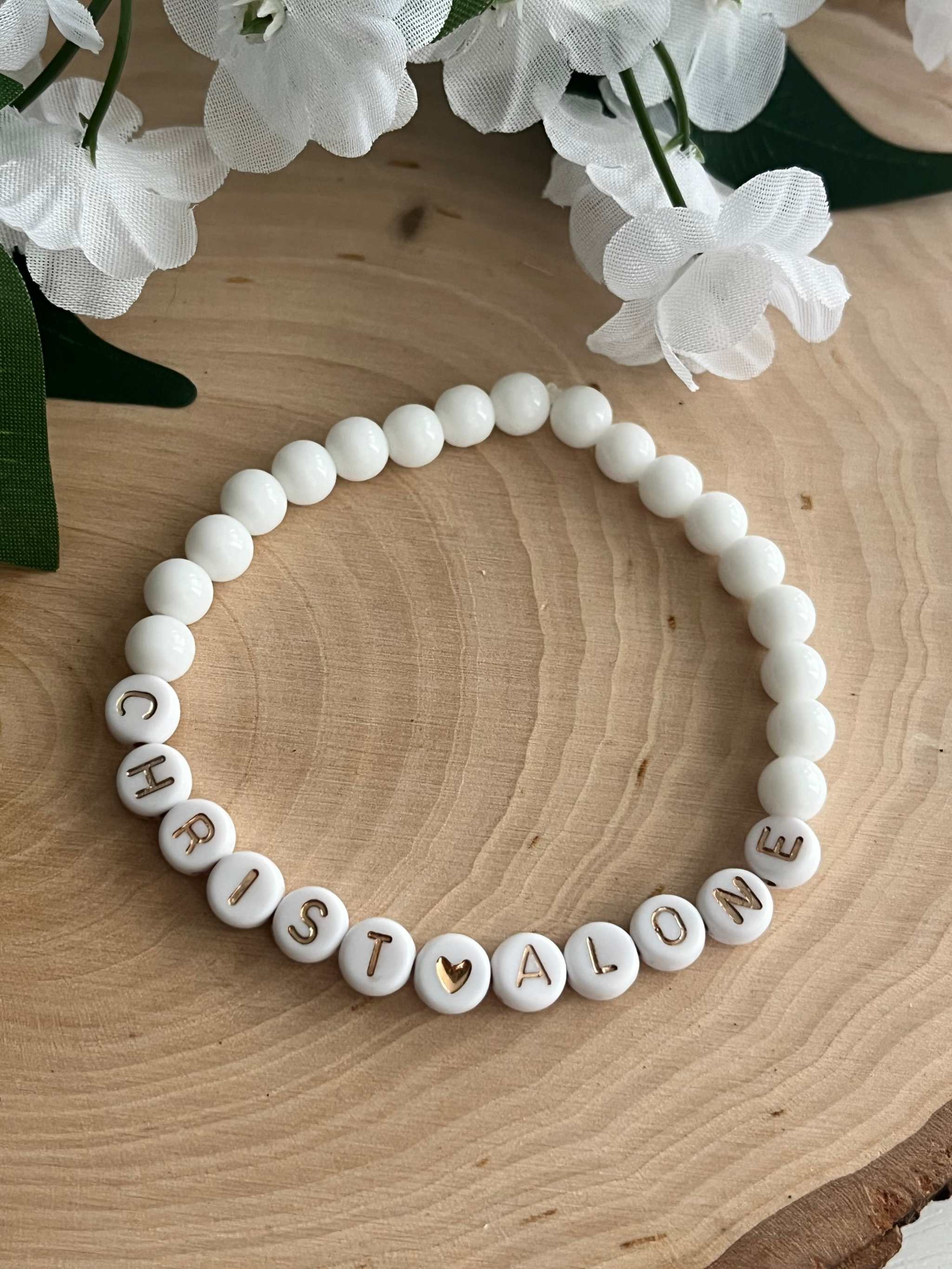 White bead bracelet with round letter beads spelling "CHRIST ALONE"