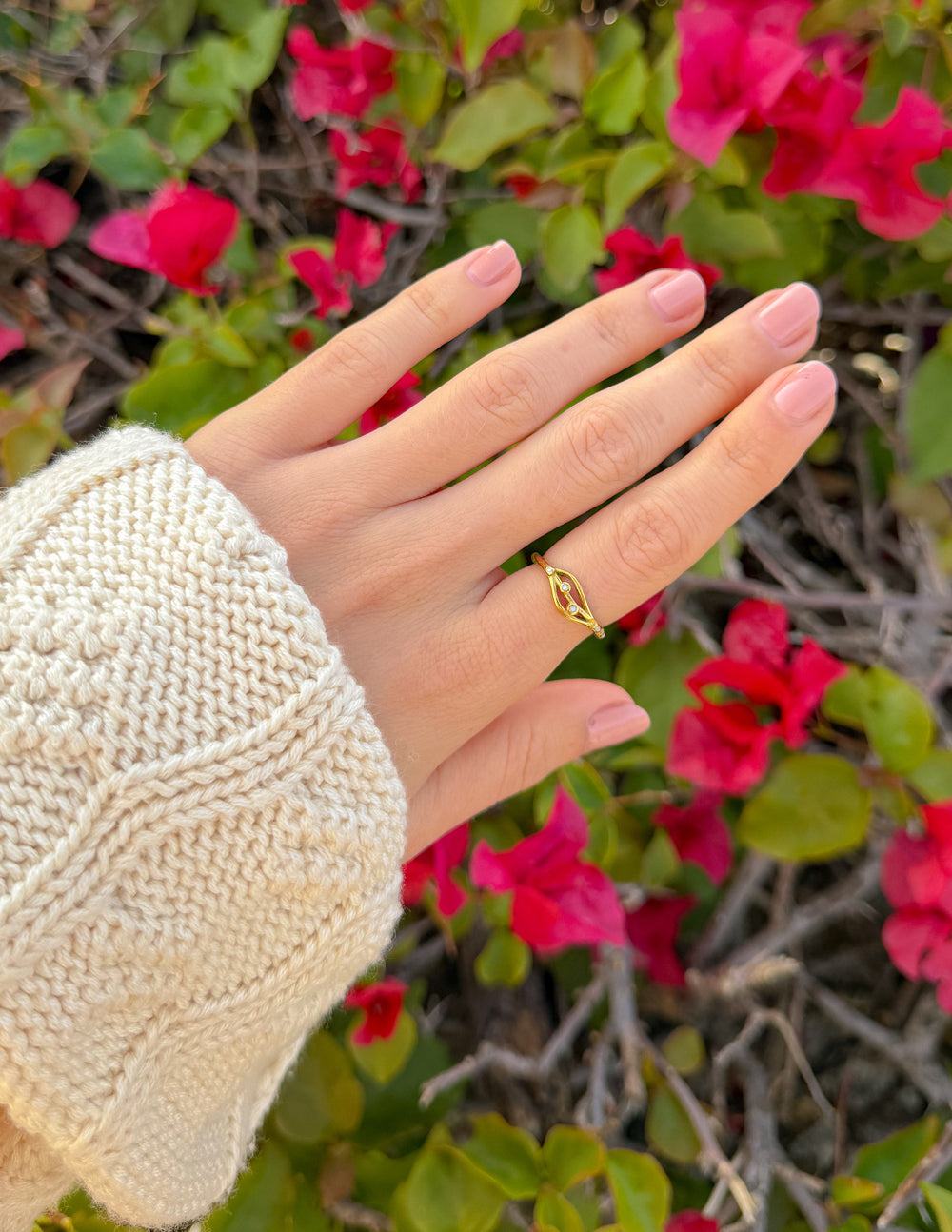 Gold-tone open ring with oval hoop and three bead-like charms, on hand