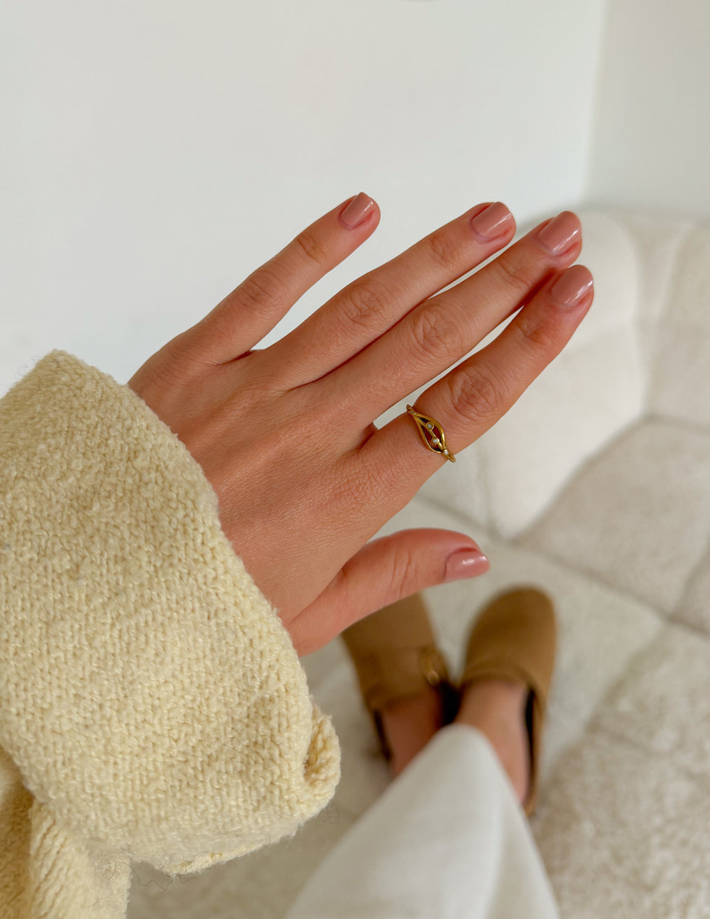 Gold-tone open ring with curved band and small bead details, worn on hand