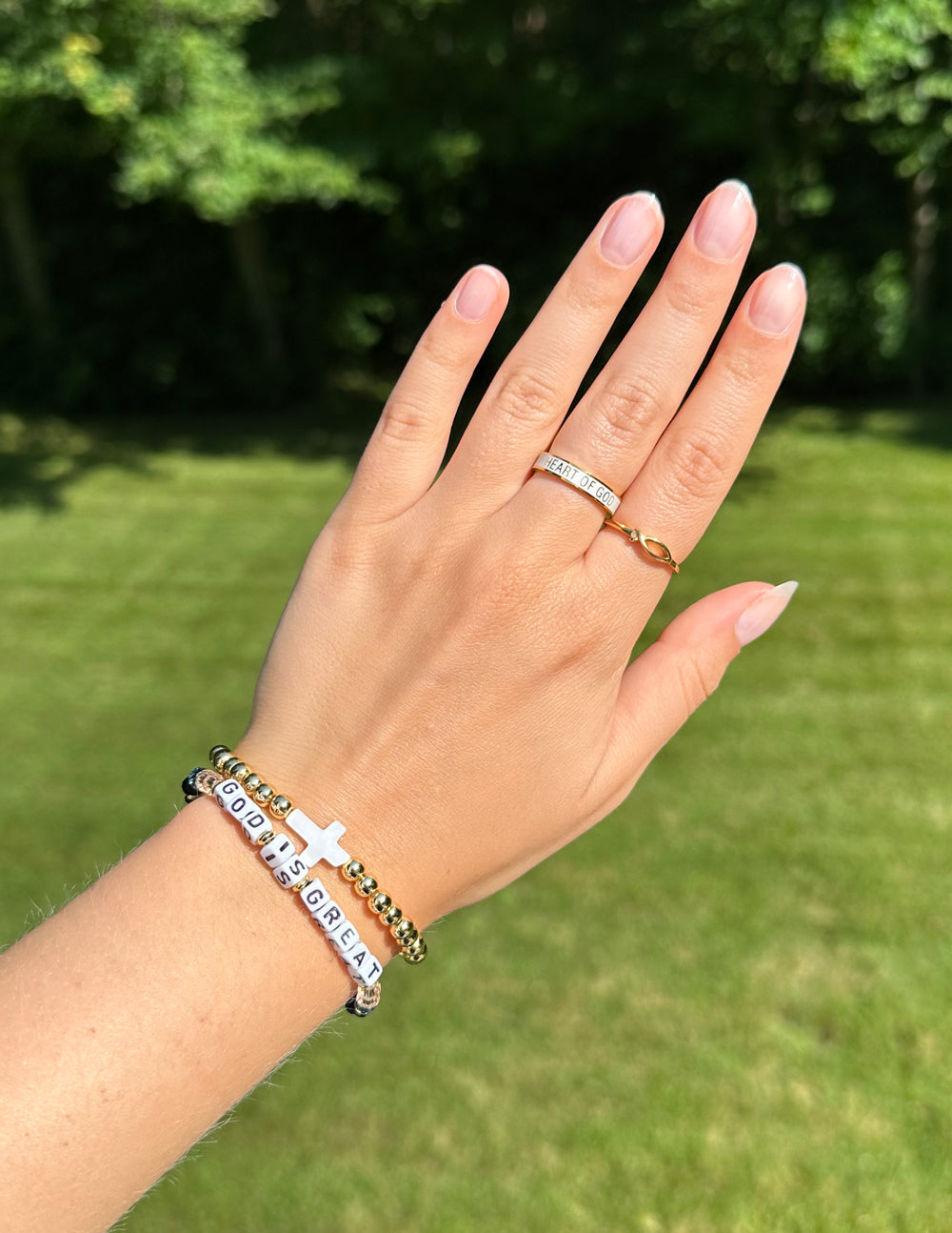 Silver ring with sparkling stones and a thin gold band on a finger