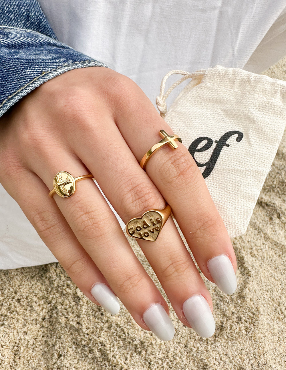 Set of gold-tone heart rings on hand; small 'God is love' text bands
