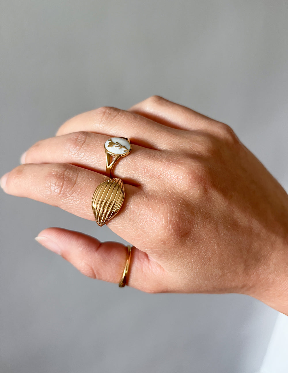 Gold-tone oval signet ring with white cameo and butterfly motif, side view