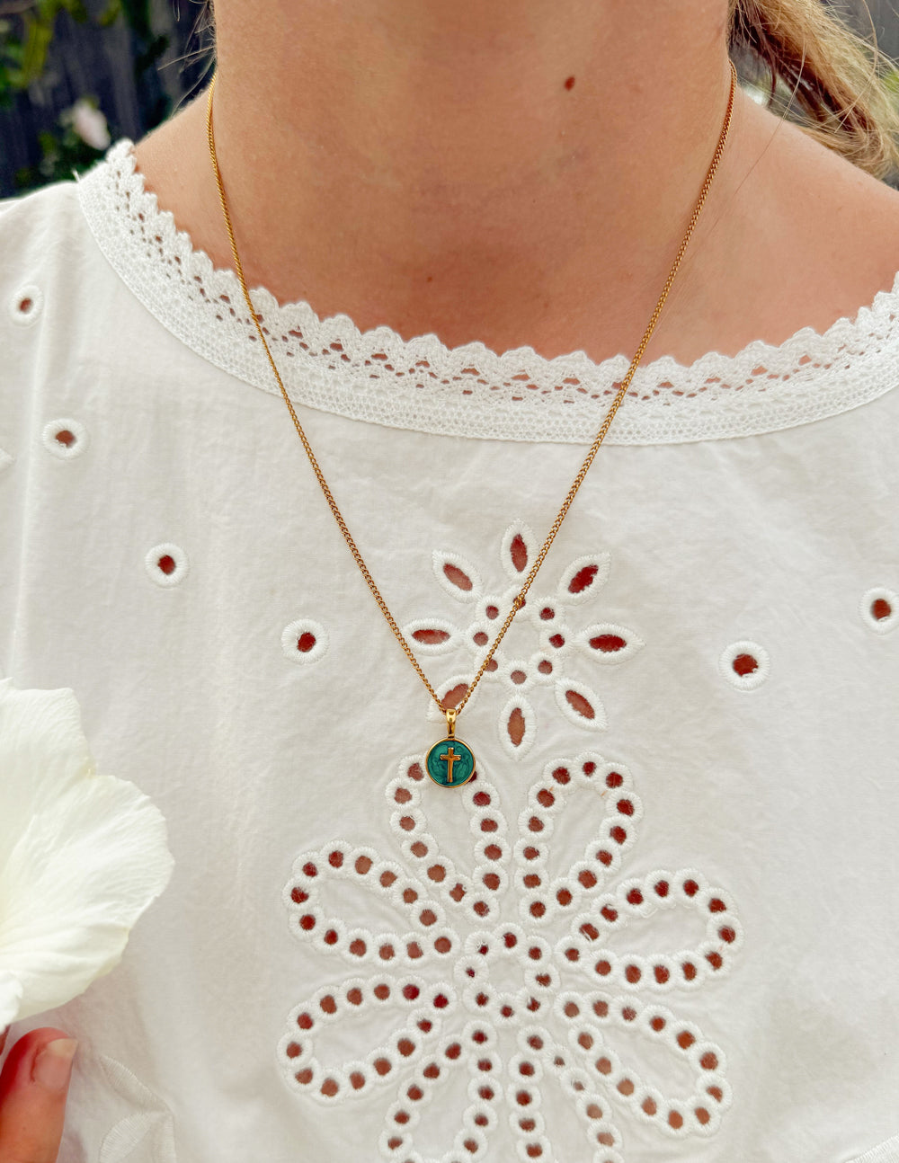 Gold chain necklace with round emerald pendant featuring a gold cross